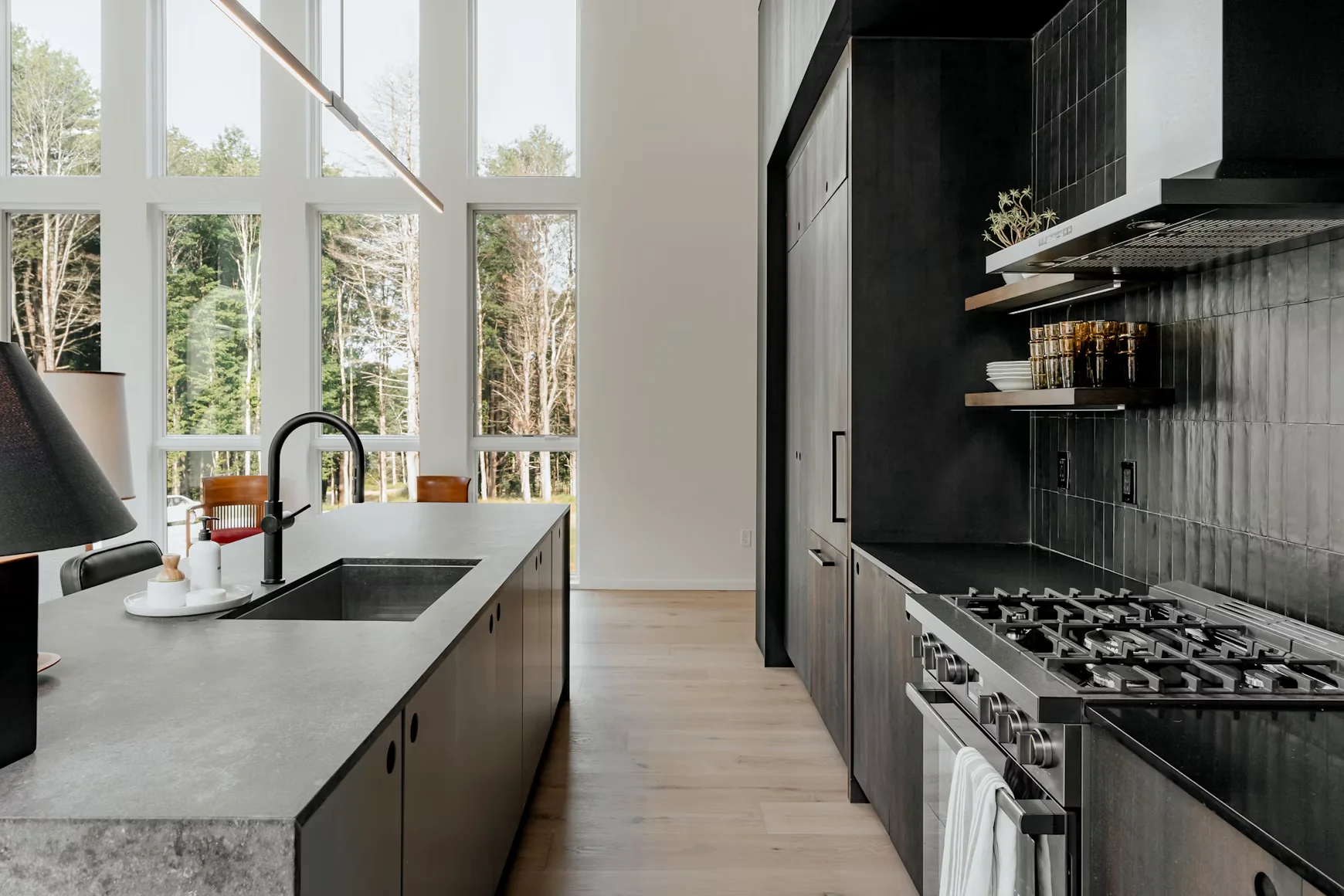 Architectural black kitchen with stone island and floor-to-ceiling windows